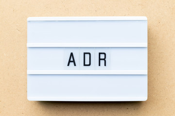 White lightbox with word ADR (Abbreviation of Adverse drug reaction) on wood background