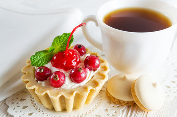 Delicious tartlet with fresh berries and cream cheese, a сup of tea and small cookies.