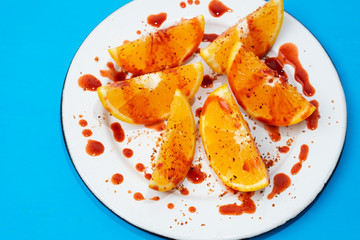 Orange slices with chilli powder and chamoy on colorful background
