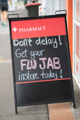 Pharmacy sign advertising in-store flu vaccination injections available.