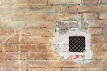 Fototapeta premium Grunge wall with a window with rusted iron grate; off center with copy space for text