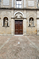 Catholic Church doors with a plaza in front and religious icon statues flanking the entrance