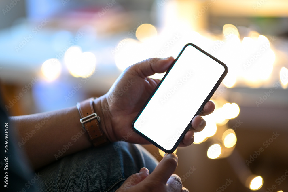 Wall mural Man holding mobile smart phone at street night with blurred background.