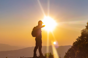 silhouette of travel man with backpack looking sunset on top mountain