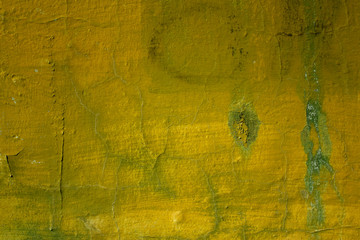 old yellow green shabby wall with cracks, white and black mold stains. rough surface texture