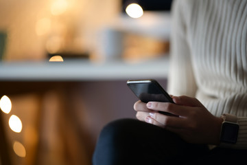 Cropped shot of woman using mobile phone sitting in cafe