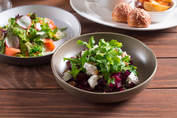 beetroot salad with blue cheese, arugula and walnut in a plate on a wooden background
