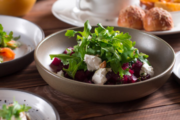 beetroot salad with blue cheese, arugula and walnut in a plate on a wooden background