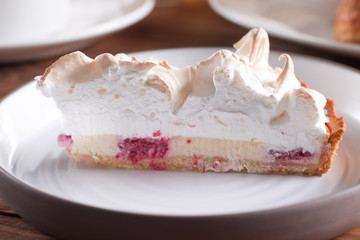 Raspberry cake with white adored meringue on a wooden table