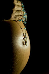 Pregnant with hands on belly and rosary, praying.