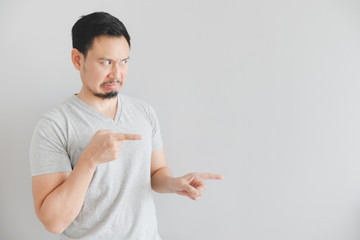 Hate face of man in grey t-shirt with hand point on empty space.