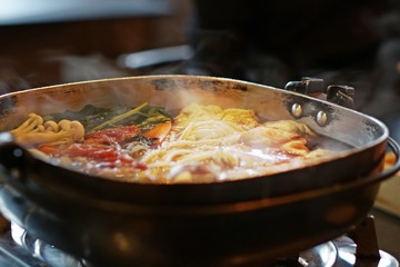 Hot pot of Japanese sukiyaki with ingredient of contrast color in a pot, meat and vegetable inside, fell hot from smoke that floats on top, traditional food of japan noodle, delicious food