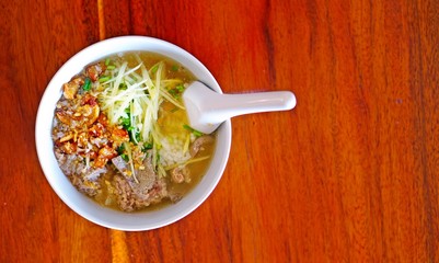 Rice soup with pork and some ingredient on top on the wood table, traditional of Thai food, good breakfast for start a day.
