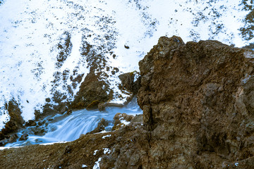 Blue waterfall flowing through snow covered rocky landscape