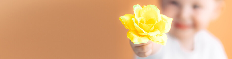 Closeup portrait happy smiling boy with orange rose. Beautiful little boy toddler giving a flower...