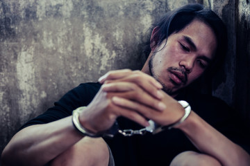 Prisoner young asian man get depressed, sad and thinking future life. Bad guy is cuffed and sit in...