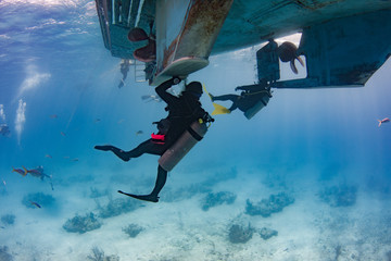Scuba Divers hold on to ropes and the hull of the boat during their safety stop after a deep water dive in the Caribbean