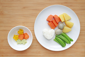 Raw of boiled vegetables baby food (carrot, egg, potato, rice and sweet pea) in white plate with frozen mashed baby food homemade in white ceramic bowl on wooden board.