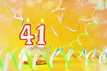 Forty one years birthday. Cupcake with burning candles in the form of number 41. Bright yellow background with copy space