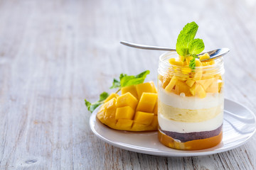 Sweet homemade Mango dessert, cheesecake, trifle, mouse in a glass jar on a light wooden background