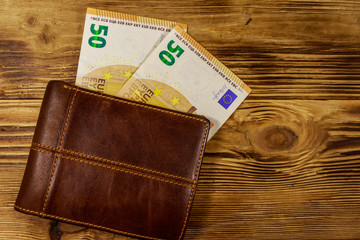 Wallet and fifty euro banknotes on wooden background
