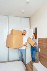Happy couple holding cardboard boxes and moving to new place