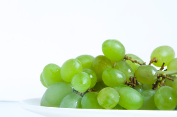 Green grapes on white plate on white background. Fresh fruit.