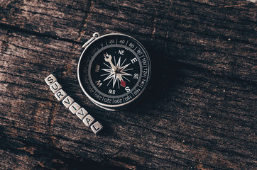 Compass on wood deck with blocks of letters making the word survival.