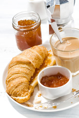 croissants with jam and coffee with milk for breakfast, vertical closeup