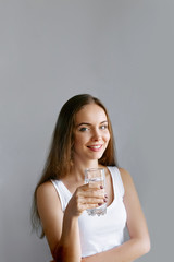 Healthy lifestyle.Young woman drinking from a glass of  fresh water. Healthcare. Drinks. Portrait of happy smiling female model holding transparent glass. Health,Beauty,Diet concept. Healthy eating.