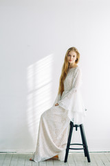 Beautiful bride sitting on a chair in the white Studio. Minimalistic wedding in European style.