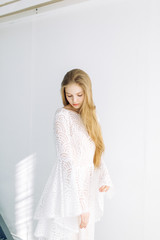 Beautiful bride on a white minimalistic background. Wedding preparations in fine art.