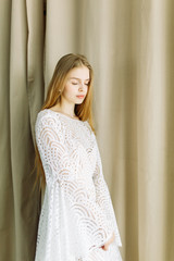 Fototapeta premium Beautiful bride on a white minimalistic background. Wedding preparations in fine art.