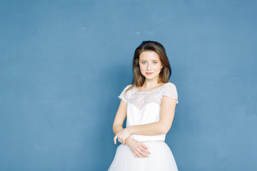 Portrait of a beautiful bride on a bright blue and red background. Minimalist white dress.