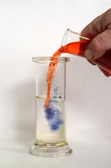 A red congored solution is poured into a clear acid solution and turns blue as the two liquids meet.