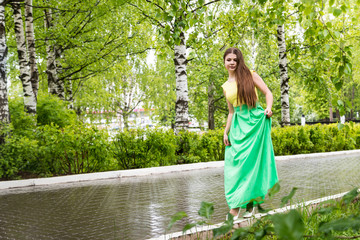 Beautiful young woman near green trees in the park