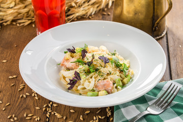 fresh salmon pasta with zucchini and glass of berry drink on wooden table
