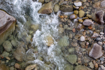 Water in the mountain raging river. Beautiful natural background of stones and water. Texture of clear water and fast river. Background to insert text. Tourism and travel.