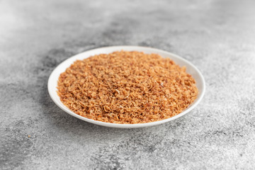 Buckwheat cereal in a white saucer on a gray concrete background
