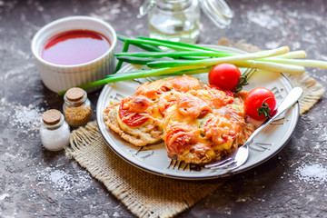 Pork chop baked with vegetables and cheese with fresh tomatoes and green onions.