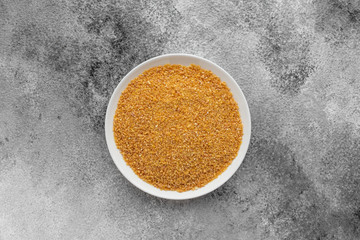 Wheat porridge in a white saucer on a gray concrete background