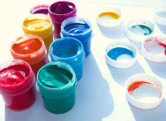 Color gouache jars on white background with shadow, caps beside