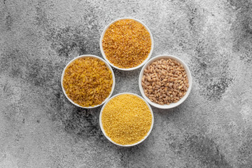 Variations of porridges and bean in white saucers on a gray concrete background