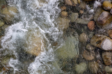 Water in the mountain raging river. Beautiful natural background of stones and water. Texture of clear water and fast river. Background to insert text. Tourism and travel.