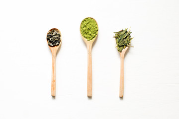 Biluochun, Matcha and Longjing. Chinese leaf and Japanese powdered green tea in a spoon on a white background. Top view and central location.