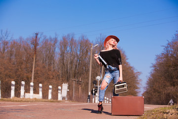 Beautiful traveling woman with retro suitcase on the road