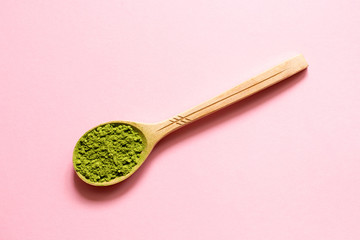 Matcha. Japanese powdered green tea in a spoon on a pink background.
