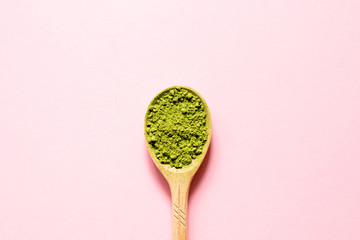 Matcha. Japanese powdered green tea in a spoon on a pink background. Top view and copy space.
