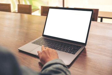 Mockup image of a woman using and touching on laptop touchpad with blank white desktop screen on wooden table