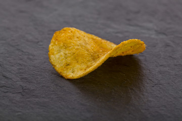crispy potato chips on a black stone background